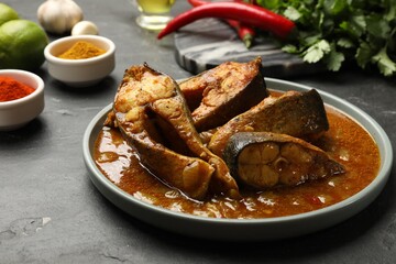 Tasty fish curry and ingredients on grey textured table, closeup. Indian cuisine