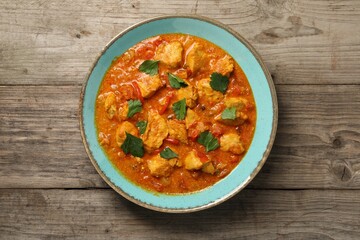 Delicious chicken curry on wooden table, top view