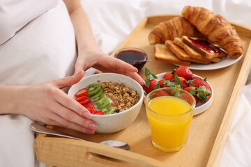Woman having tasty breakfast in bed, closeup