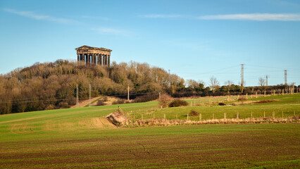 Penshaw Monument above cultivated field. Penshaw Monument is a copy of the Greek Temple of Hephaestus in Athens. Erected in 1844 the folly stands 20 metres high and dominates the skyline of Wearside - obrazy, fototapety, plakaty