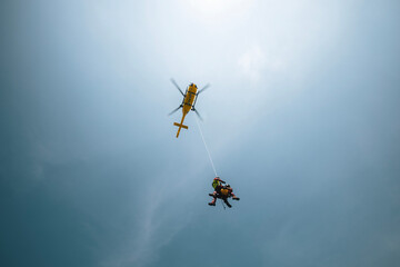 Two paramedics hanging on rope under flying helicopter emergency medical service. Themes rescue,...