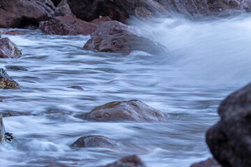 Naklejka premium Waves breaking over rocks on the sea shore with the waves smoothed by long exposure