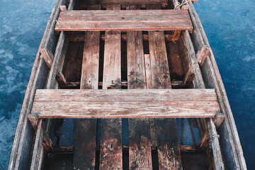 Fototapeta na wymiar Close up of a weathered wooden rowboat on the frozen lake.