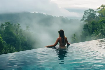 Foto op Plexiglas Tranquil Retreat: Young Woman Swimming in Resort Pool Overlooking Lush Mountain Vistas © Murda