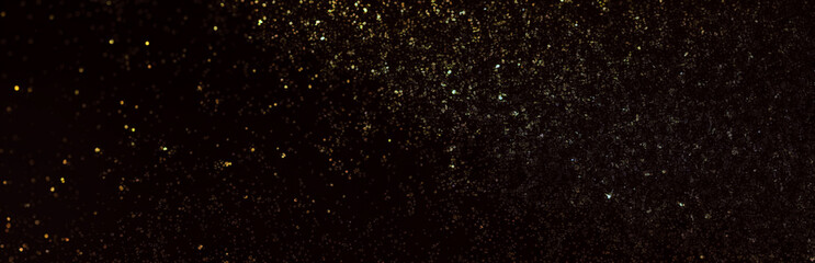 A black background with gold glitter particles floating across it