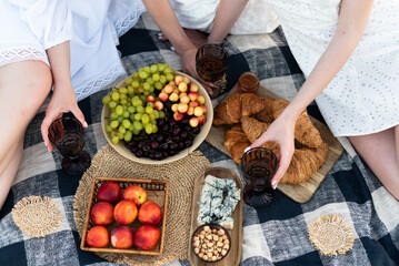 Picnic in nature, croissants, peaches, grapes, cherries, cheese, hazelnuts, glasses with an...