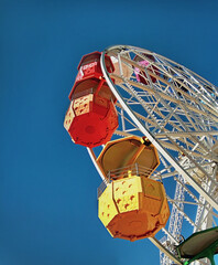 Ferris wheel with colorful booths against a blue sky