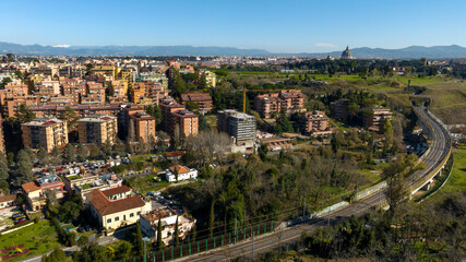 Fototapeta na wymiar Aerial view of the Balduina neighborhood in Rome, Italy. In the background the dome of St. Peter's Basilica in Vatican City. In the foreground Monte Ciocci and Ettore Scola park.