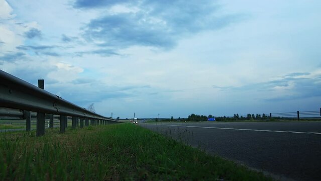 Huckepack trailer box lory cargo truck with refrigerated container driving on highway under overpass tonight countryside, out of town. Export import by logistic company. Traffic barrier guard rail