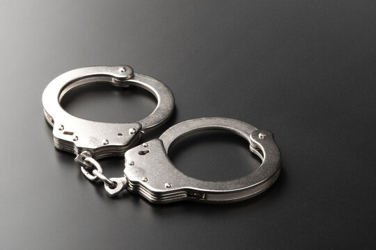 Police handcuffs on dark background with copy space