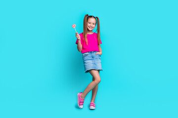 Full length photo of stylish schoolgirl with ponytails wear pink t-shirt hold lollipop arm in...