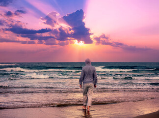 Seascape in the evening with a beautiful sky. A man walks barefoot on the beach and looks at a...