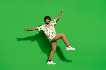 Full length photo of positive sweet arabian man wear print shirt dancing having fun isolated green color background
