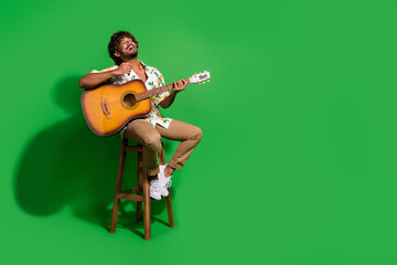 Full body photo of attractive young man sit chair sing play guitar wear trendy citrus print clothes...