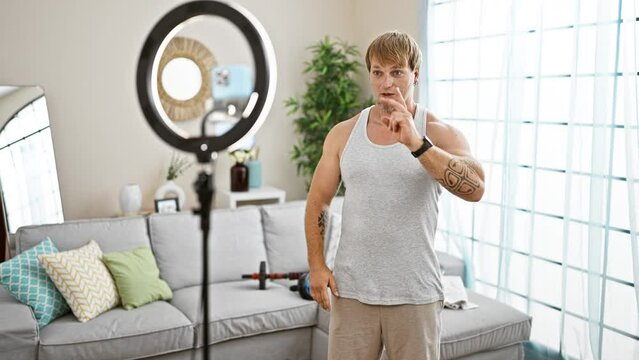 Young blond man with beard filming workout in a modern living room with ring light