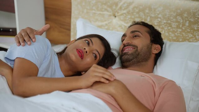 Relaxed romantic Indian couples talking together by hugging each other at bedroom - concept of relationship bonding, affection and companionship