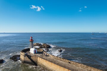 Sentinel of the Sea: Majestic Lighthouse Perched on Stone Wall Beside Foz Do Douro Beach in Porto