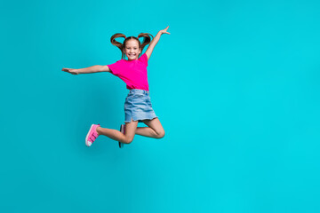Fototapeta na wymiar Full size photo of good mood girl dressed pink t-shirt flying palms like wings near empty space isolated on turquoise color background