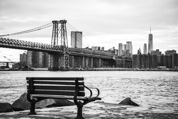 An empty rustic wooden bench with nostalgic Manhattan Skyline and Williamsburg Bridge on a snowy...