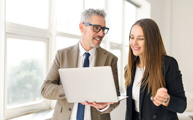 Senior businessman with grey hair shares a light-hearted moment with a female colleague while...