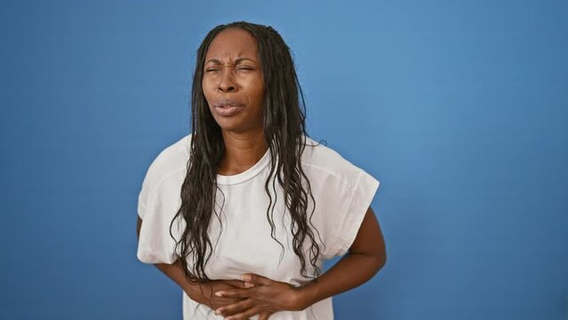 African american woman with curly hair in pain against blue isolated background