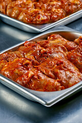Fresh chicken wings and thighs marinated in red sauce at the butcher shop