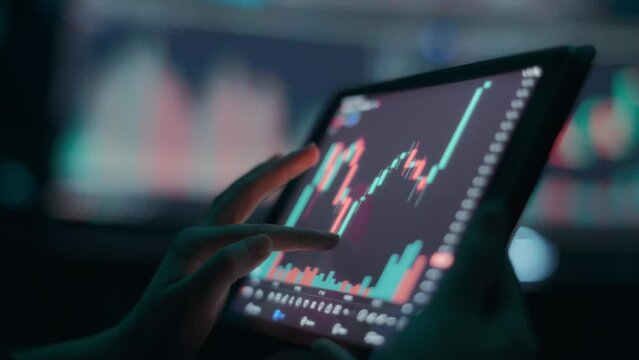 Person analyzing stock market graph on a tablet touchscreen. Close up, slow motion. 