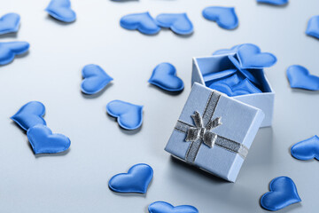 Gift box with blue hearts on blue background.