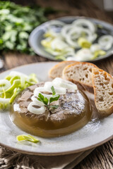 Homemade pork aspic, meat jelly with onion and leek in a white plate