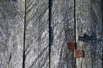 Fragment of an old door with a rusty curtain. Texture of old weathered boards as a background.