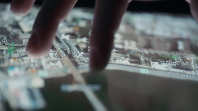 Fingers zooming out on a 3D city map on a tablet. Close up, slow motion. 