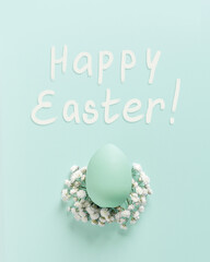 Happy Easter Greeting with Turquoise Egg and White Flowers on Pastel mint Background, Pastel colored painted chicken egg on Bed of White Baby's,  Easter celebration minimal holiday concept