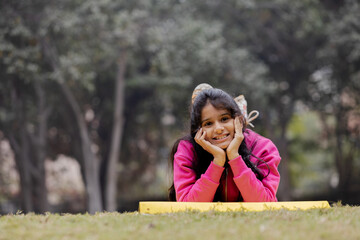 Portrait of Indian Girl Relaxing on Grass in Garden looking into Camera