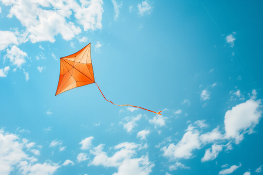 Orange kite flying on the blue sky