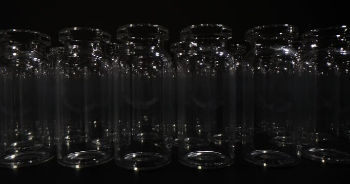 Collection of many small empty scientific vials on black background. Medical utensils for vaccines