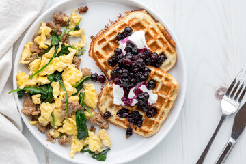 Gourmet scrambled eggs with protein waffles topped with sauteed berries.