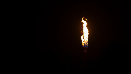Fire flame from top of gas refinery plant during it burning on the black background.