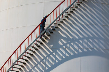 A male walking the upstairs inspection visual record storage tank oil stairs