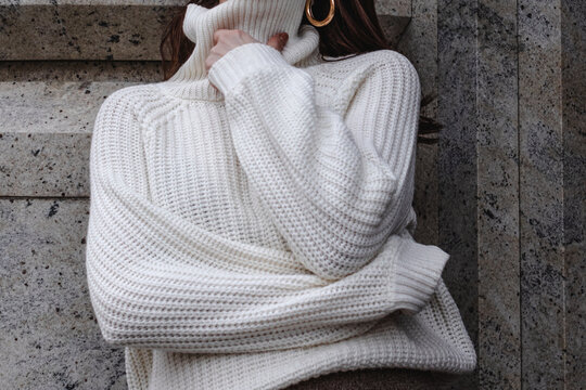 Close-up details of a warm winter knitted white turtleneck sweater. Women's fashionable casual wear