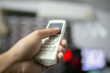 Close up of a hand holding a remote control in a blurred background