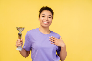 Portrait of excited attractive African American woman, winner holding triumph cup, looking at camera