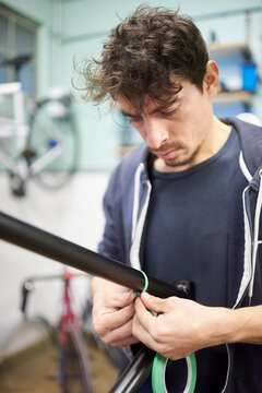 Man preparing a bicycle frame with masking tape for a custom painting design.