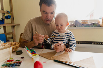 Happy Easter! Father with son painting eggs at home.