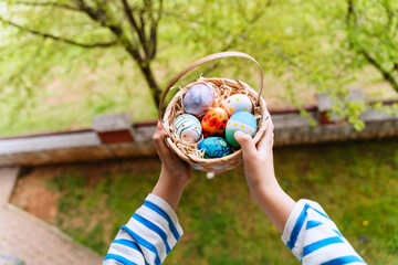 Colorful Easter eggs in basket. Kids hunt for eggs outdoors. - obrazy, fototapety, plakaty