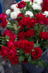 Red and white roses in a plastic vase on the floor.