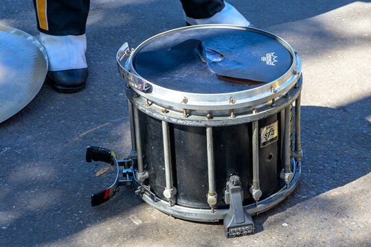 Worn Tom-Tom Drum on the Ground with Shoes of Drummer and Cymbal Blurred in the Background on Mardi Gras parade route on February 13, 2024 in New Orleans, LA, USA