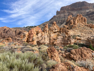 Hiking around Piedras Amarillas rock formation in El Teide crater on Tenerife. Orange volcanic cliffs.