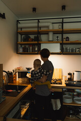 A mother holds her daughter in her arms in the kitchen. Normal mom routine. Lifestyle