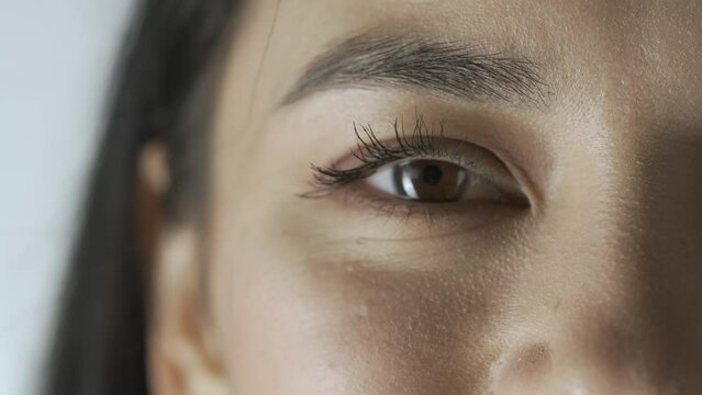 Macro shot of female model face. Asian young woman macro shot of the face parts eyes and lips, model smiling shows teeth looks at the camera.