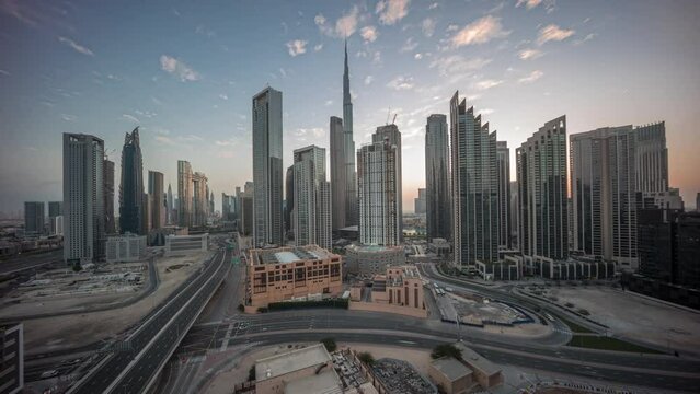 Aerial panoramic view of Dubai Downtown skyline with many towers night to day transition timelapse. Business area in smart urban city. Skyscrapers and high-rise buildings from above before sunrise UAE